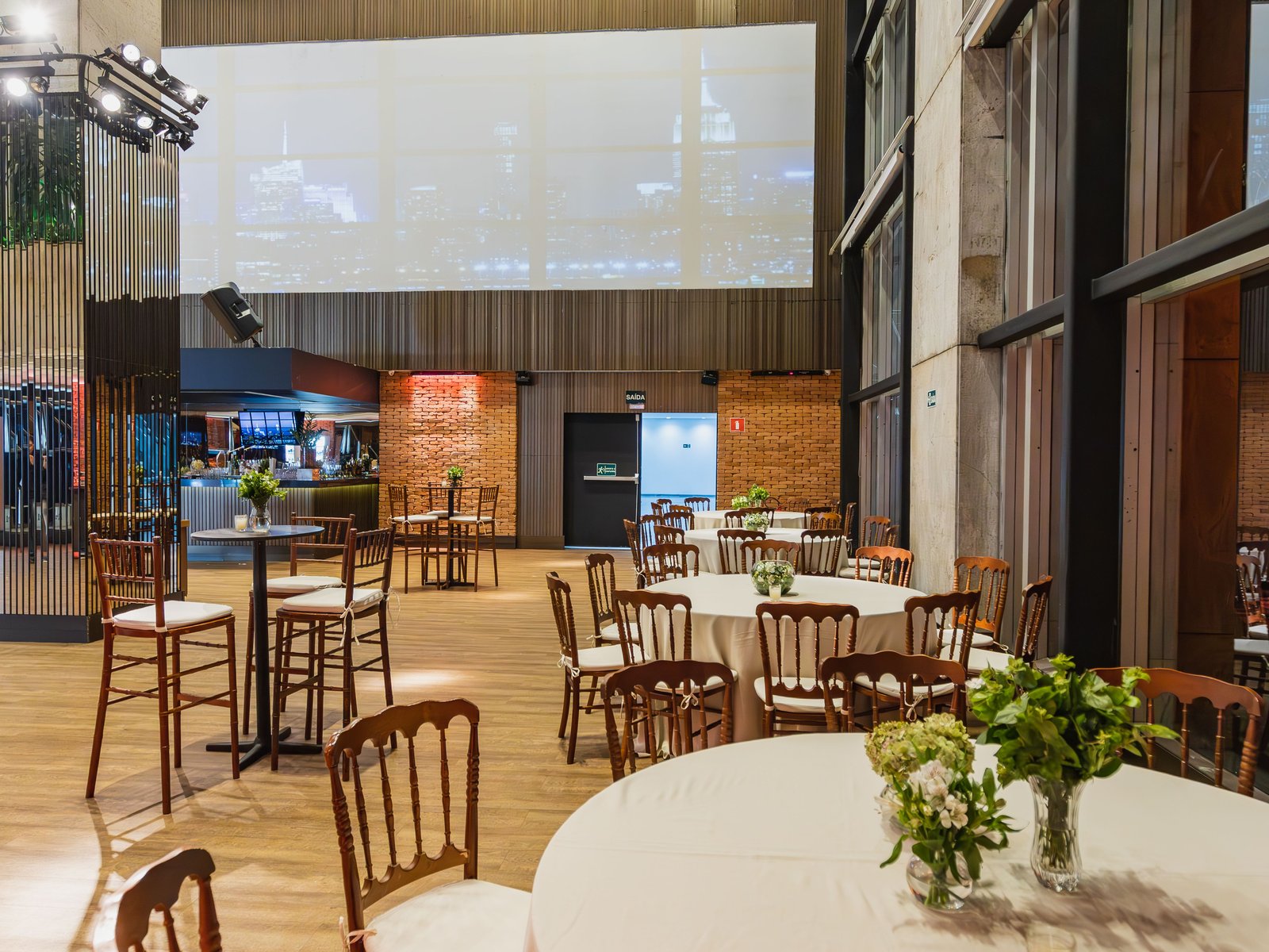 A fully set up event space with round tables, seating and AV screen